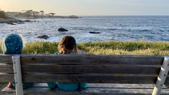 kids on a bench looking out over the water in Monterey